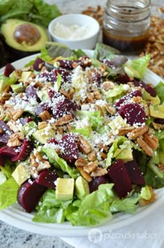 a salad with beets, lettuce and nuts on it sitting on a plate