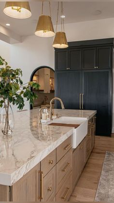 a large kitchen with marble counter tops and gold accents on the cabinets, along with two vases filled with flowers