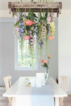 a table with flowers hanging from it's ceiling and two mugs on the table