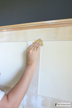 a woman is painting the wall with white paint