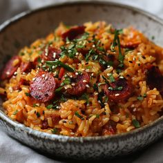 a bowl filled with rice and sausage on top of a table