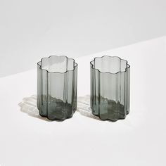 two clear glass vases sitting on top of a white table next to each other