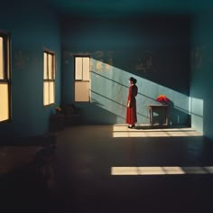 a woman standing in an empty room with sunlight coming through the windows and casting shadows on the wall