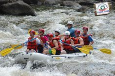 a group of people riding on the back of a raft down a white water river