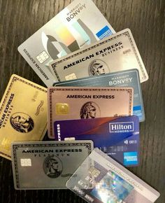 several credit cards stacked on top of each other in front of a wooden table with the words american express written on it