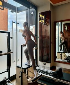 a woman is standing on a machine in front of a mirror