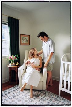 a man standing next to a woman sitting in a chair