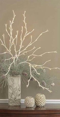 a vase filled with branches and pine cones on top of a table