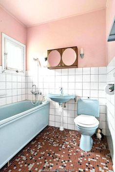 a bathroom with pink walls and white tiles on the floor, including a blue bathtub