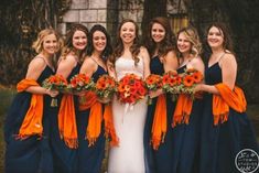 a group of women standing next to each other wearing dresses and holding bouquets in their hands