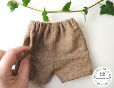 someone is sewing the bottom part of a pair of brown shorts with leaves on it