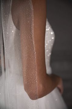 the back of a bride's wedding dress, with water droplets on her veil