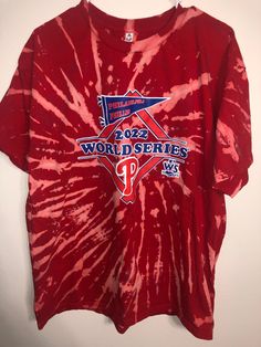 a red tie - dye shirt with the word world series on it, hanging up against a wall