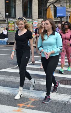 two women walking across a cross walk in the street