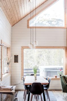 a dining room table and chairs in front of a large window with wooden beams on the ceiling