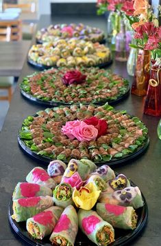 there are many plates with food on them that have flowers in the middle and one is rolled up