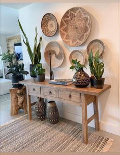 a wooden table topped with potted plants next to a wall mounted wicker fan