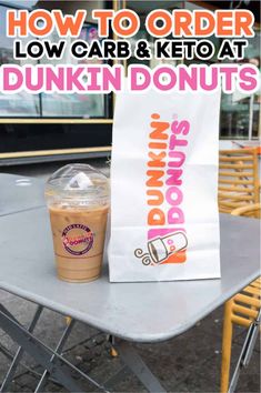 a dunkin donuts bag sitting on top of a table next to a drink