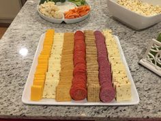 an assortment of cheeses, crackers and meats on a counter with bowls of vegetables