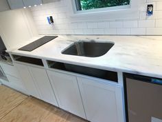 a kitchen counter with a sink and dishwasher on it in front of a window