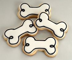 four decorated cookies with black and white icing on top of each cookie, one is shaped like a dog bone