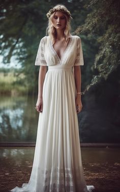 a woman wearing a white dress standing in front of trees