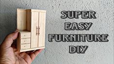 a hand holding a miniature wooden cabinet with the words, super easy furniture diy