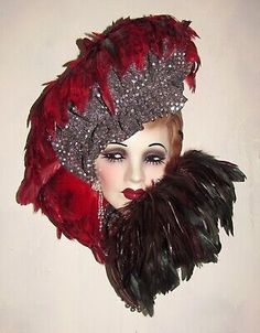 a mannequin head wearing a red hat with feathers