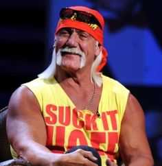 an old man in a yellow shirt and red bandanna sitting on a chair with his arms crossed