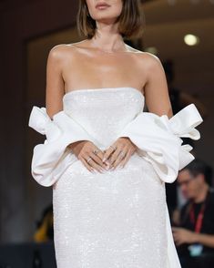 a woman in a white dress on the runway