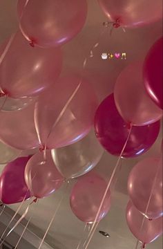 pink and white balloons are hanging from the ceiling