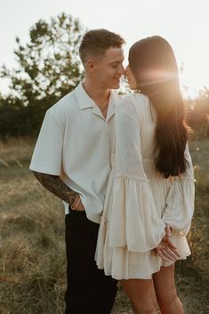 a man and woman standing next to each other on top of a grass covered field