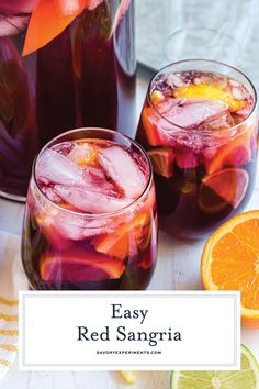 two glasses filled with red sangria next to sliced oranges