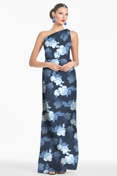 a woman in a blue floral print dress with one shoulder and an asymmetrical neckline