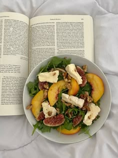 an open book is next to a bowl of salad