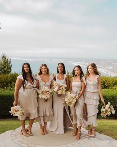 the bridesmaids are all dressed in different styles and colors, posing for a photo