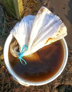 a white bucket filled with liquid and a piece of bread wrapped in a blue string