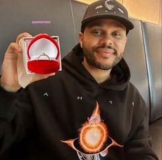 a man in a black hoodie is holding up a ring that has been placed on it