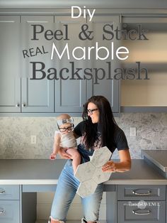 a woman holding a baby in her arms while sitting on top of a kitchen counter