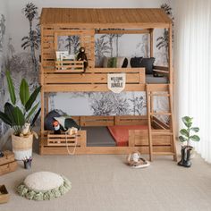 a wooden bunk bed sitting next to a plant in a room with wallpaper on the walls