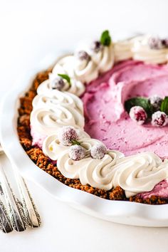 a pie with white frosting and cranberries on top is sitting on a plate