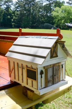 a dog house sitting on top of a wooden platform in the middle of a field