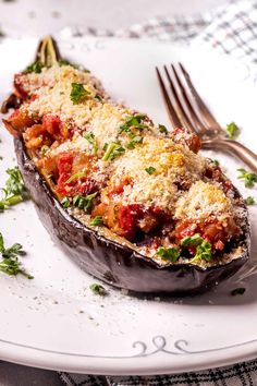 an eggplant stuffed with tomatoes and parmesan cheese on a white plate