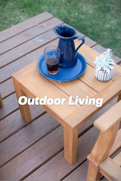 a wooden table with a blue plate and cup on it, next to a chair