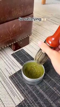 a person is using a brush to paint a green substance in a small white bowl