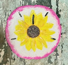 a painted piece of fruit with a yellow flower on the center and black dots in the middle