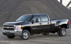 a black pickup truck parked in front of a pile of dirt and gravel hills behind it