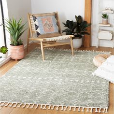 a living room area with a chair, rug and potted plants