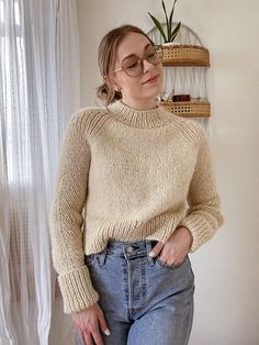 a woman wearing glasses standing in front of a window with her hands on her hips