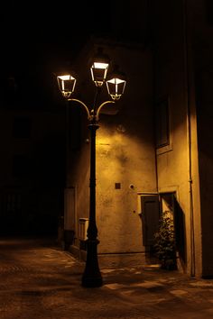 a lamp post in the middle of an empty street at night with no one on it